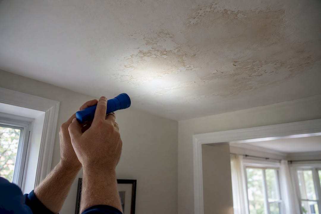 Landlord hands inspecting ceiling damage